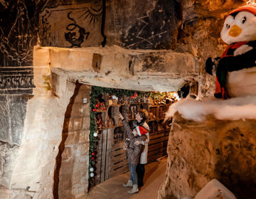 Meisje met kerstmuts en opa wijzend naar chocola in een kerstgrot